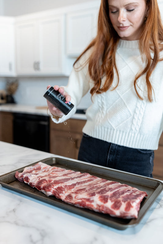 Women sprinkling pepper on pork ribs