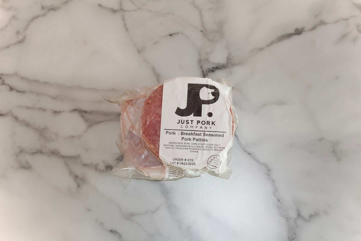 Packaged meat with 'Just Pork' label on a marble surface