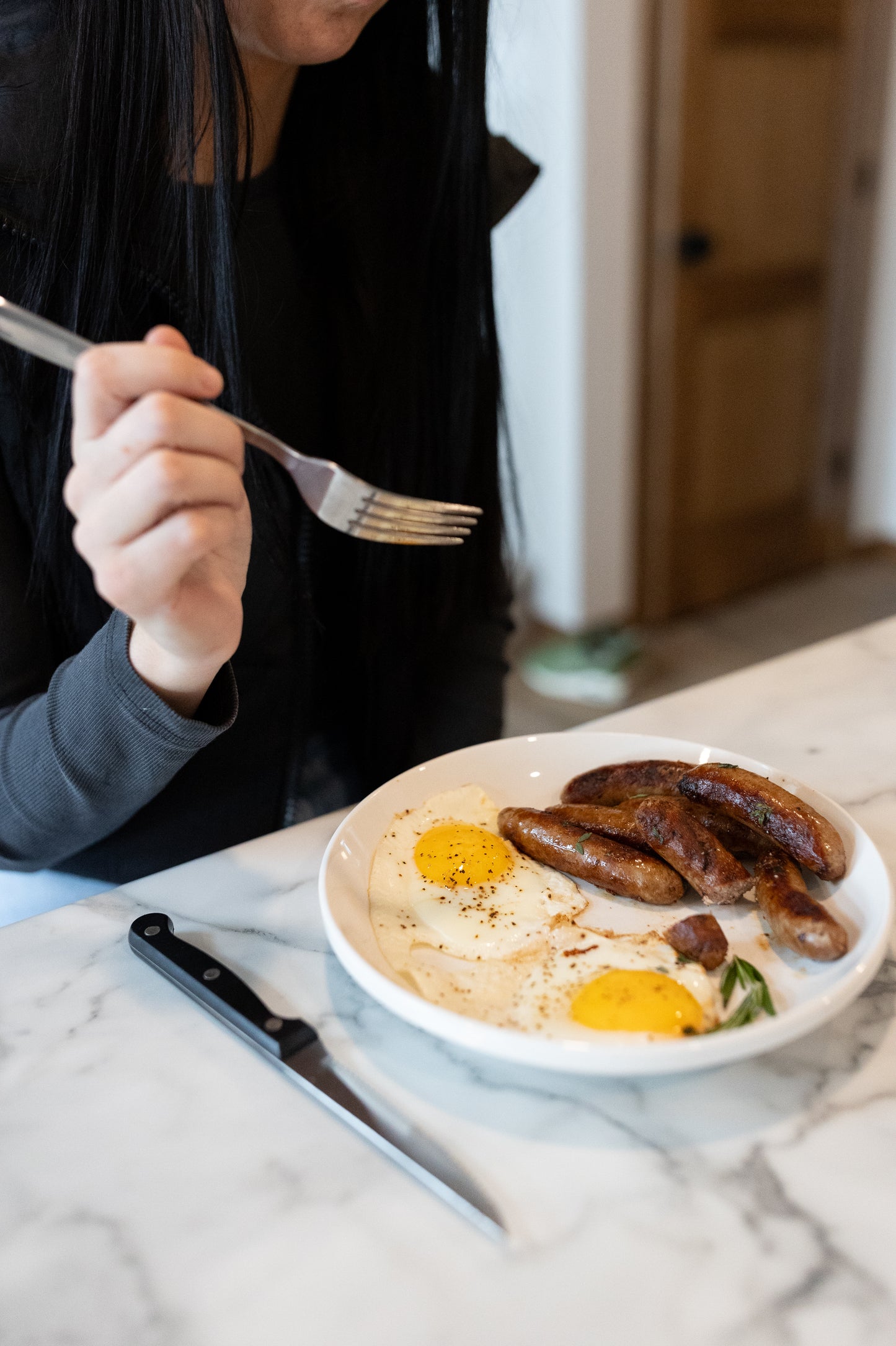 Women eating a breakfast plate with sausage links and eggs; Minnesota-raised pork with no added hormones or fillers