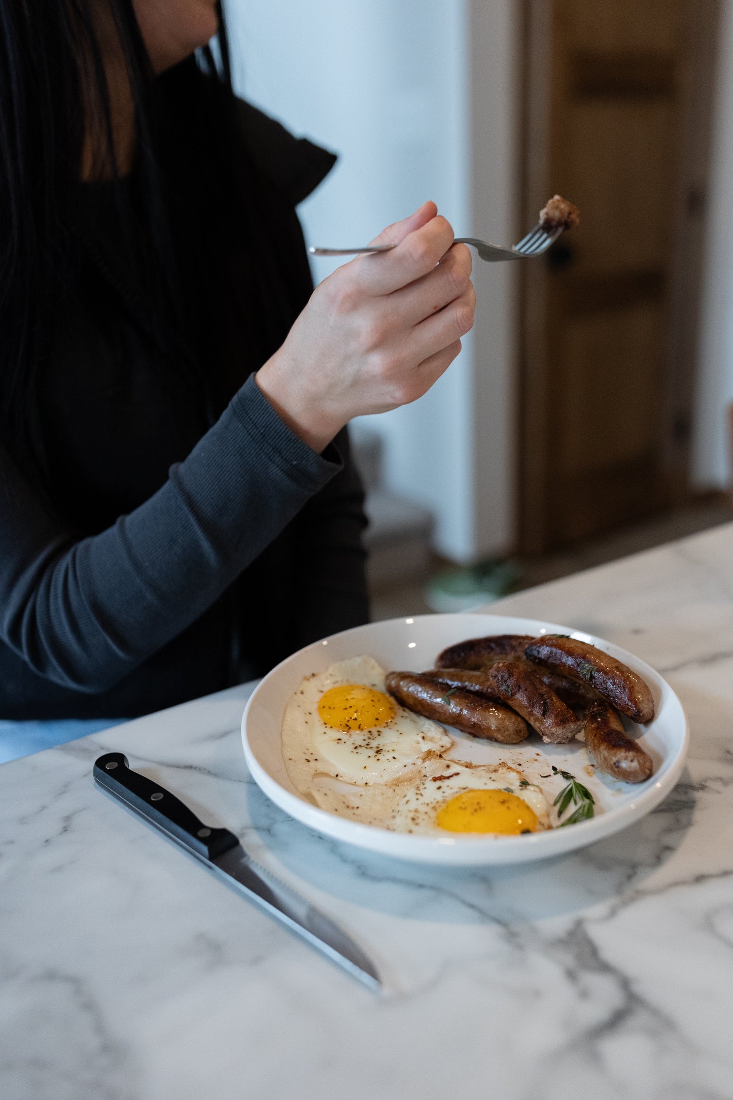 Women taking a bit of a sausage link; Healthy pork options delivered from a local farm