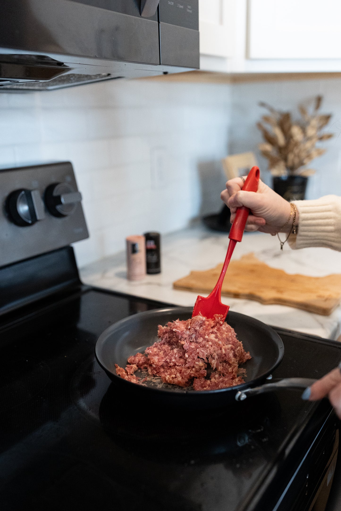 Women cooking ground pork on the stove top; Premium pork with no hormones