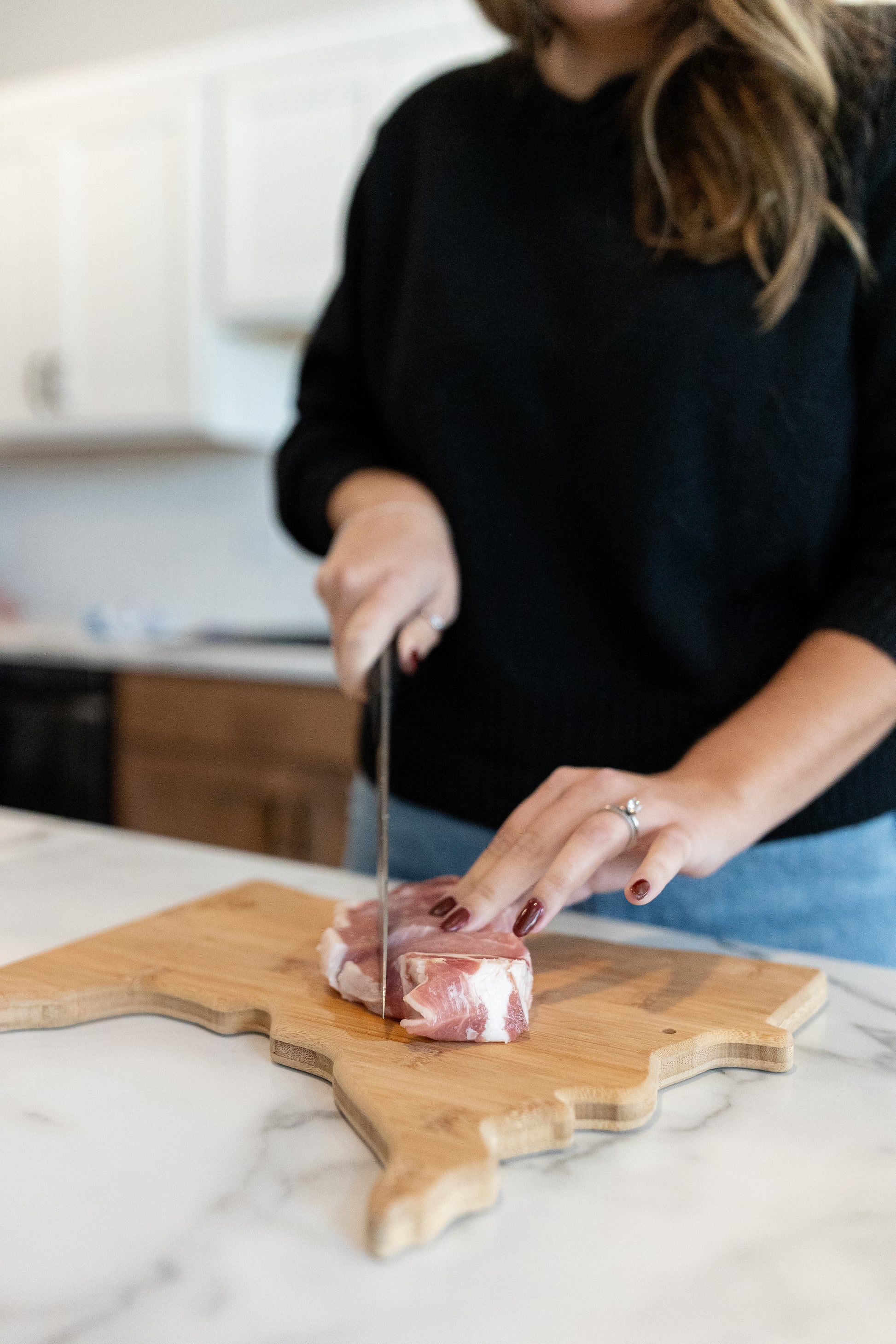 Women slicing a pork chop; Minnesota-raised pork with no added hormones or fillers